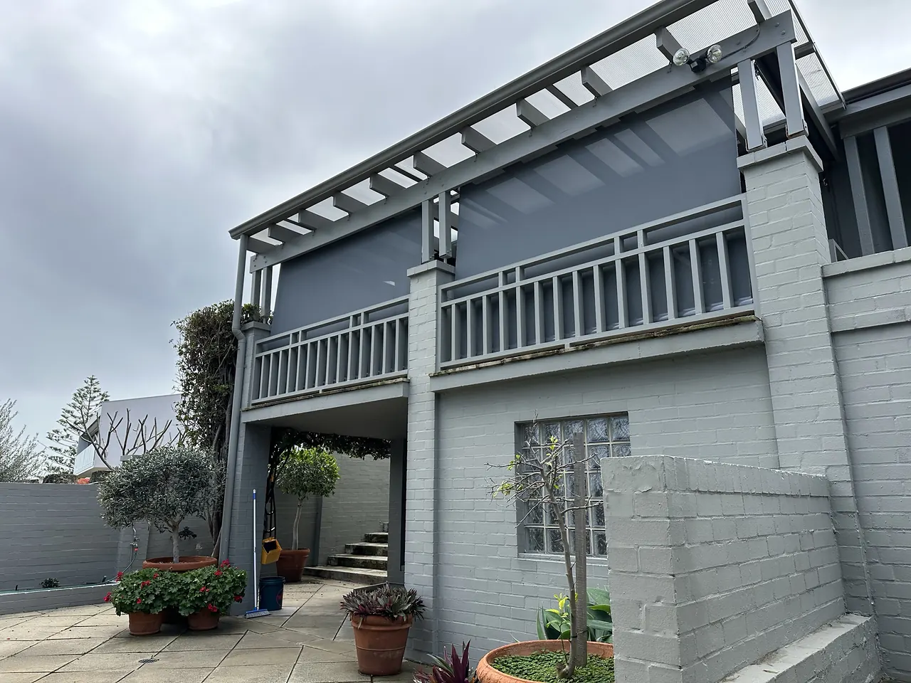 Grey outdoor blinds enclosing a first-floor balcony