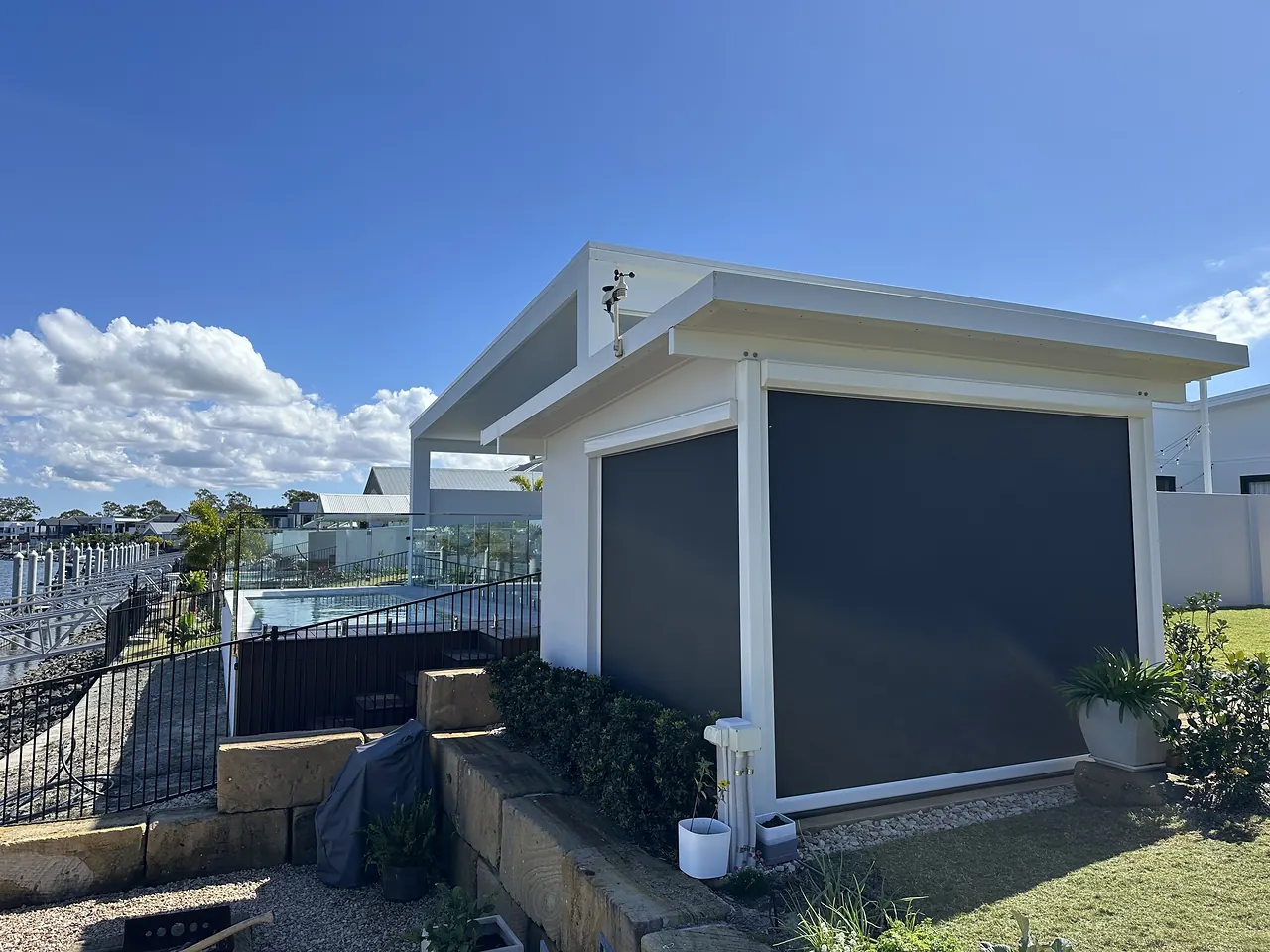 Charcoal outdoor blinds on a pavilion beside a canal