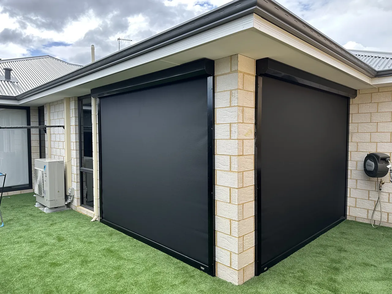 Charcoal zip blinds wrapping a limestone corner alfresco