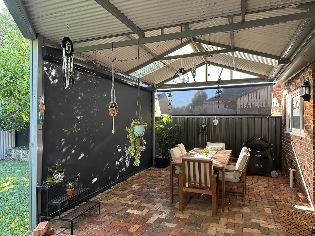 Courtyard pergola with an outdoor dining table and a charcoal side blind