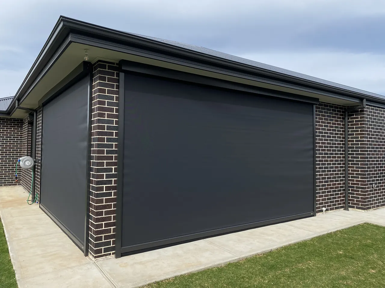 Charcoal zip blinds on a dark brick alfresco