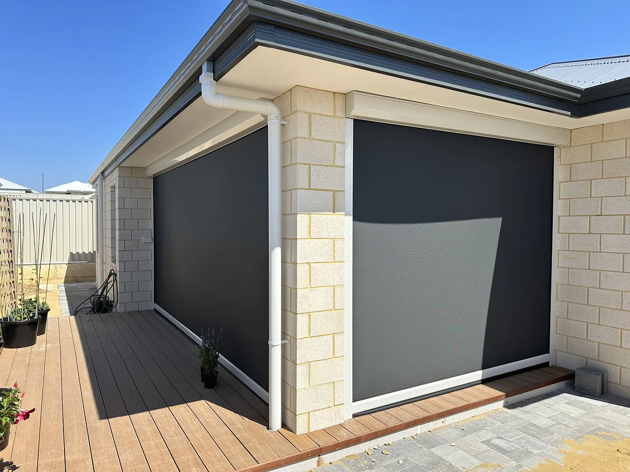 Charcoal zip blinds on a limestone alfresco with a timber deck