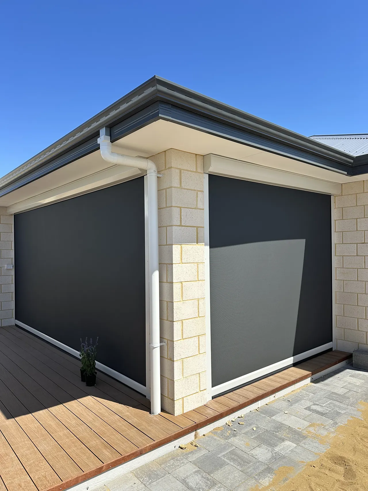 Charcoal zip blinds on a limestone alfresco, seen from the deck