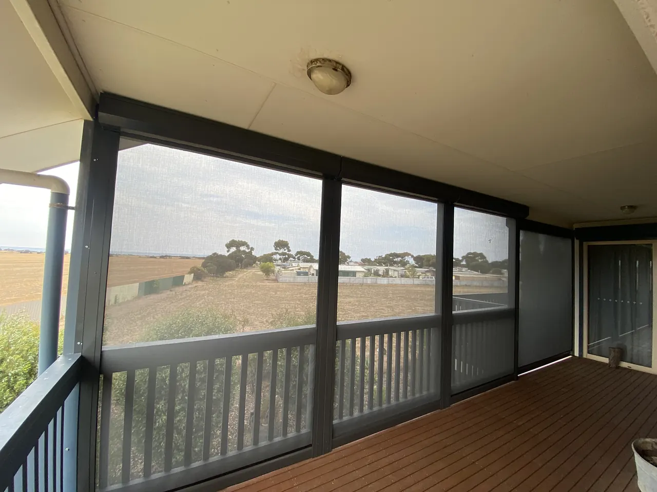 Verandah enclosed with outdoor blinds that keep the paddock view