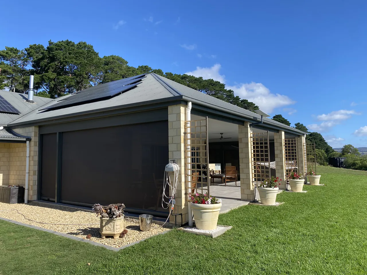 Long alfresco on a lawn, enclosed with charcoal outdoor blinds