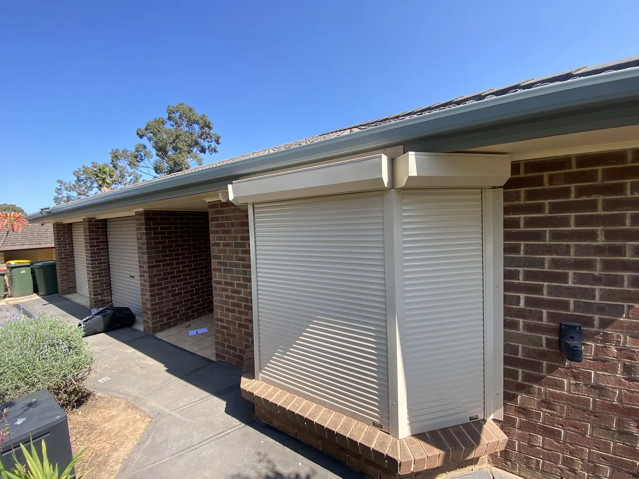 Cream roller shutters on a red brick bay window