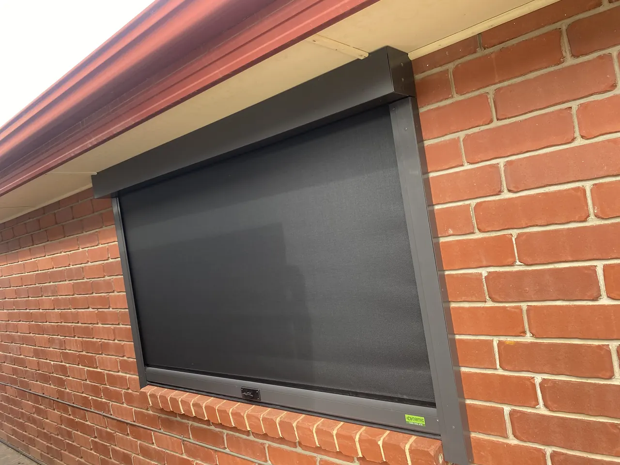 Charcoal roller shutter on a red brick wall