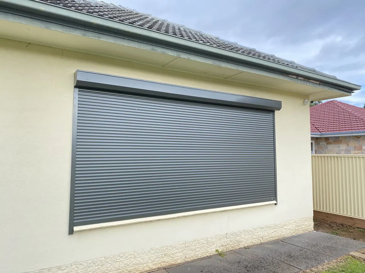 Charcoal roller shutter on a cream rendered home