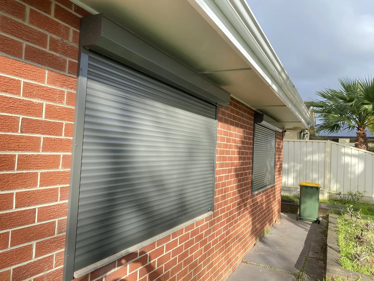 Grey roller shutter on a red brick home