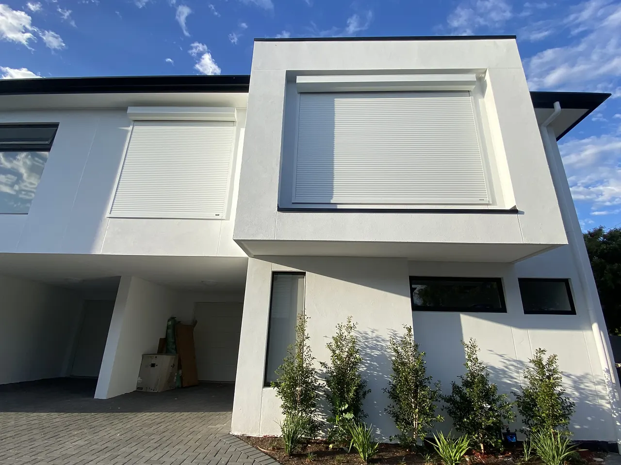 White roller shutter set into the upper window of a modern two-storey home