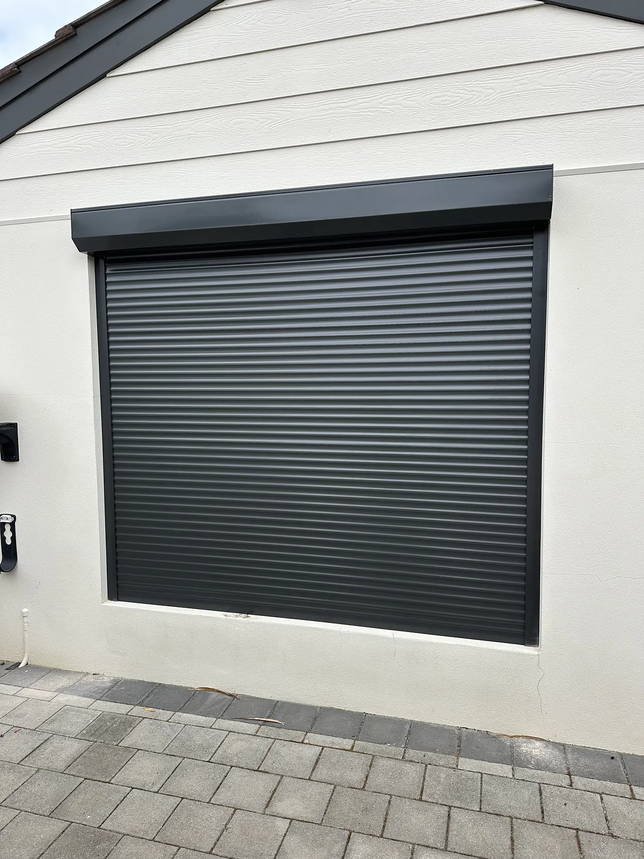 Charcoal roller shutter on a white rendered wall