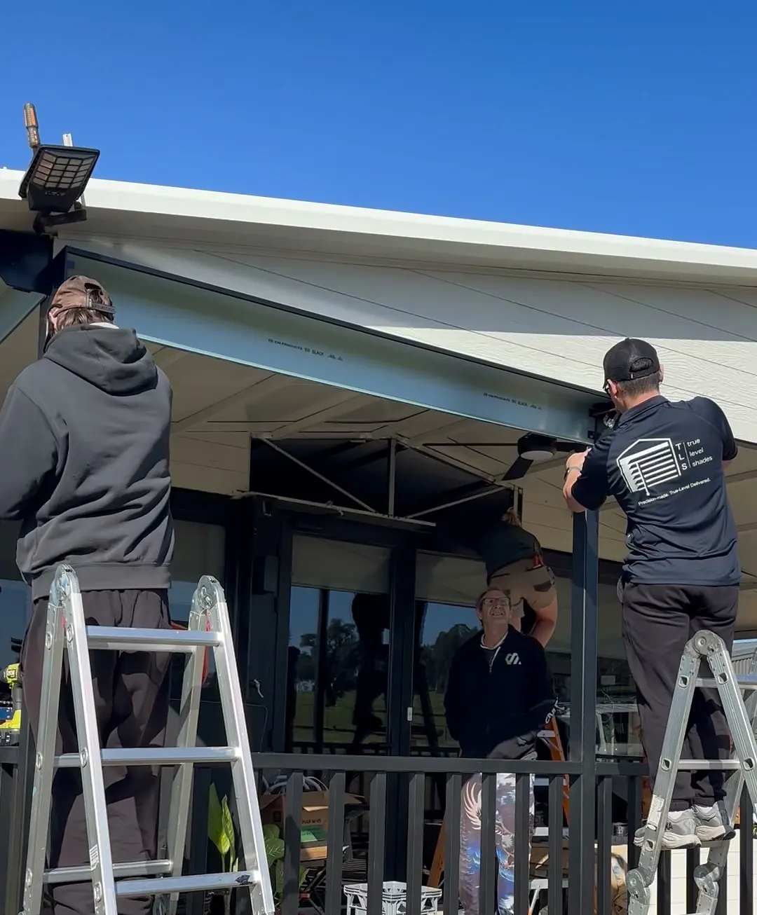 Two TrueLevel installers in branded polos fixing a blind headbox into place